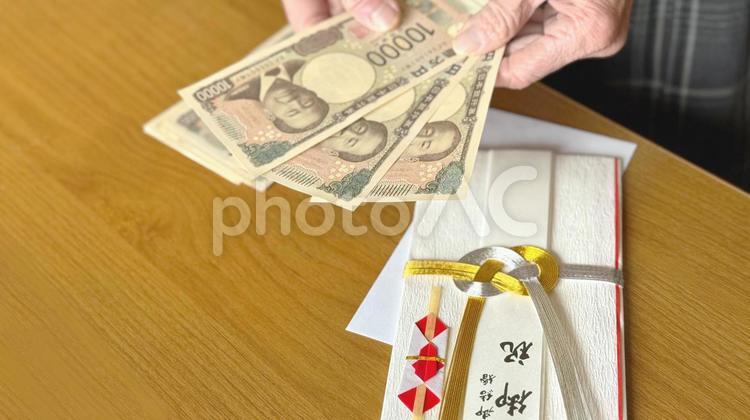 ご祝儀袋の上で3万円を持つ高齢女性の手元 ご祝儀袋,結婚式,お祝いの写真素材