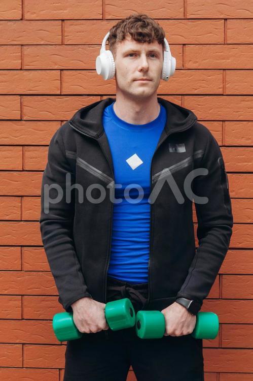 ダンベルを持ってヘッドフォンをしている男性 男性,人物,ヘッドフォンの写真素材