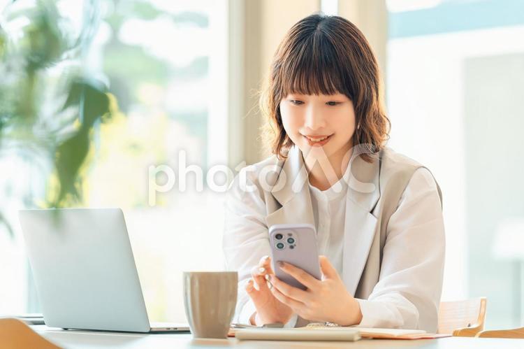 スマホを使う笑顔の女性・ビジネスウーマン 女性,ビジネス,ビジネスウーマンの写真素材