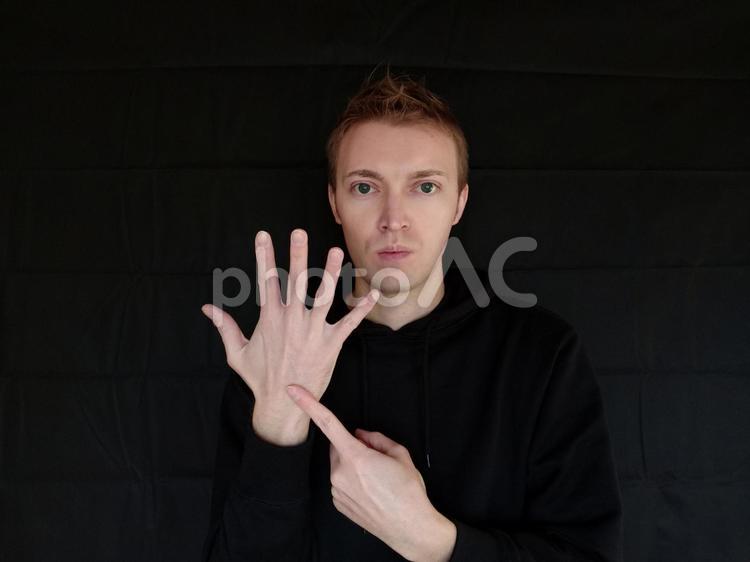 6をジェスチャーで表している外国人男性　黒バック 六,6,ろくの写真素材