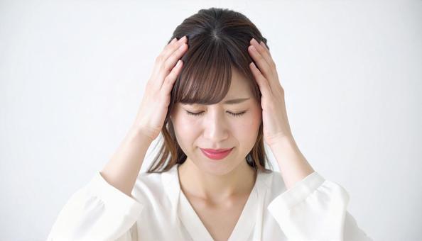 頭を押さえて辛そうな女性のクローズアップ 頭を押さえて辛そうな女性のクローズアップの写真