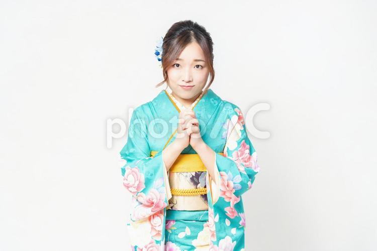 白背景の前に立って、お願いのジェスチャーをする振袖を着た女性 女性,お願い,謝るの写真素材