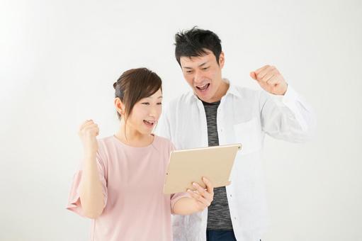 A man and a woman exciting when looking at a tablet A man and a woman exciting when looking at a tablet