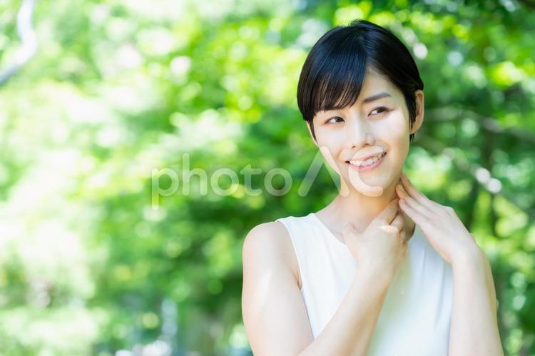 緑の中でスキンケアをする若い女性 スキンケア,ビューティー,女性の写真素材