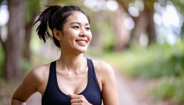 緑の多い公園をランニングする日本人女性 緑の多い公園をランニングする日本人女性の写真