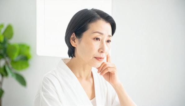 ほうれい線を気にしてほほを触る中年の女性の写真