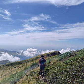 山頂の尾根を歩く人の写真