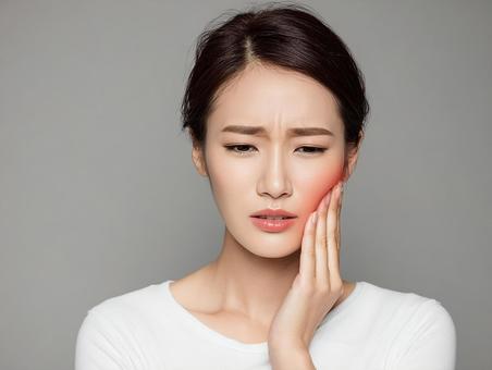 頬を押さえる女性の医療イメージ 頬を押さえる女性の医療イメージの写真