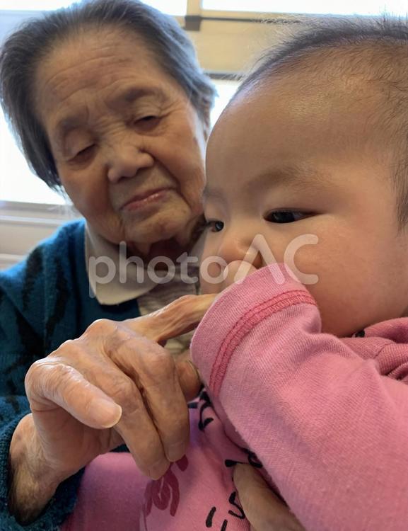 ひいおばあちゃんの指を食べようとする孫 祖母,ひいおばあちゃん,大正の写真素材