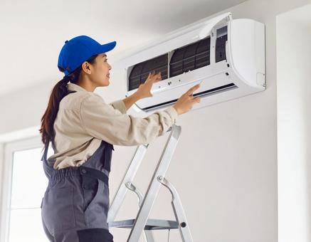 エアコン室内機を修理する女性技術者 エアコン室内機を修理する女性技術者の写真