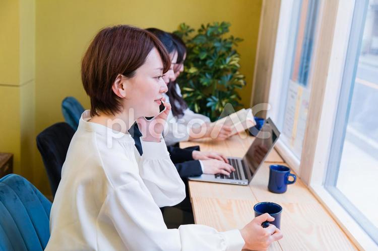 カフェの窓際カウンター席にいる女性（スマホ・笑顔） スマートフォン,横顔,スマホの写真素材