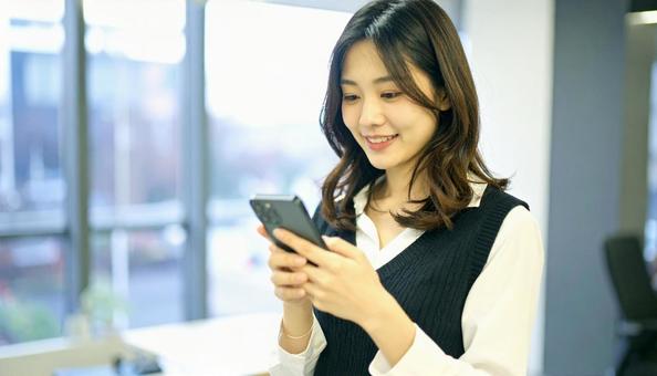 スマホを確認するビジネス女性 スマホを確認するビジネス女性の写真
