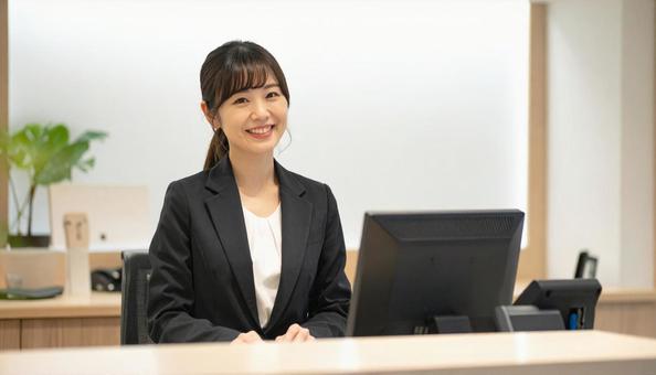 笑顔で対応する女性の受付嬢 笑顔で対応する女性の受付嬢の写真