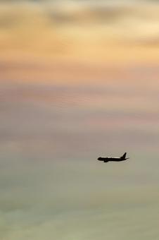 虹色の夕暮れ空を飛ぶ飛行機シルエット 虹色の夕暮れ空を飛ぶ飛行機シルエットの写真