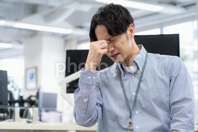 体調の悪い若い男性エンジニア ビジネス,眼精疲労,疲れ目の写真素材