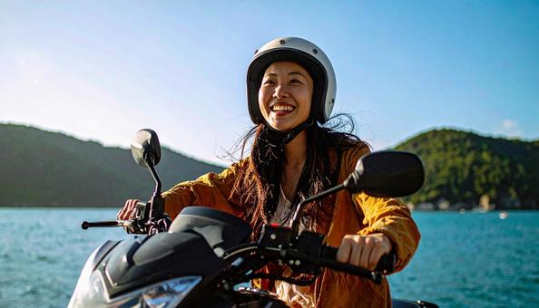 休日に海辺をバイクでツーリングする女性 休日に海辺をバイクでツーリングする女性の写真