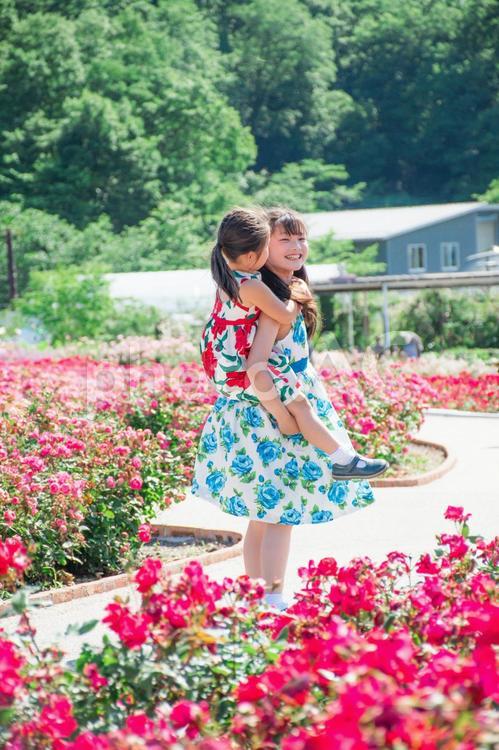 妹をおんぶするお姉ちゃん 子供,花,笑顔の写真素材
