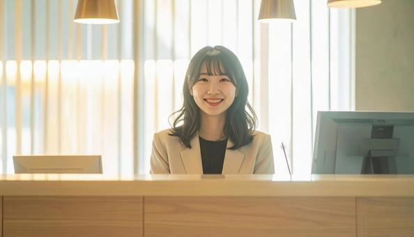 笑顔で対応する女性の受付嬢 笑顔で対応する女性の受付嬢の写真