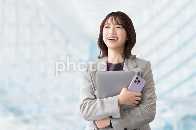 パソコンとスマホを持つ笑顔の女性 女性,ビジネス,笑顔の写真素材