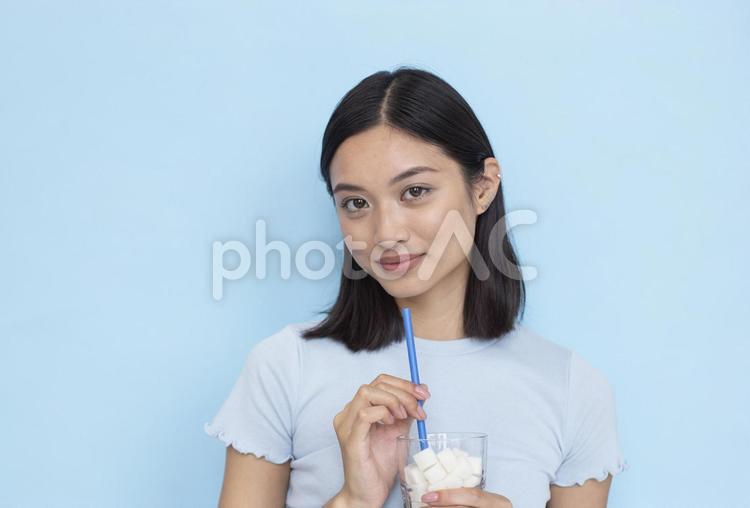 角砂糖のたくさん入った飲料を持っている女性1 女性,ブルー,カメラ目線の写真素材