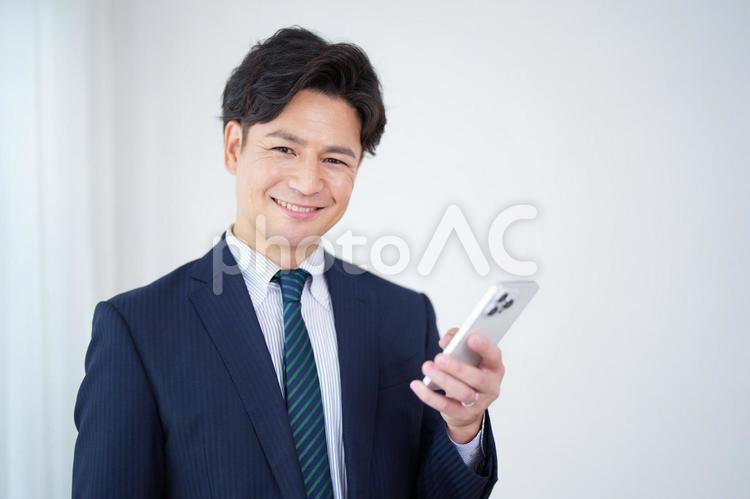 スマートフォンを使うカメラ目線の塾講師 塾,人物,男性の写真素材