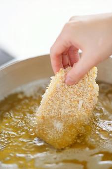 とんかつを揚げようとしている手元 とんかつを揚げようとしている手元の写真