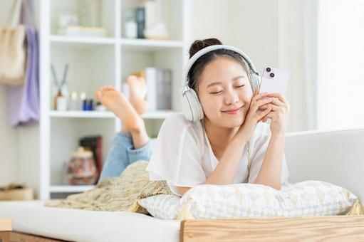 リビングでくつろぐ若い女性 リビングでくつろぐ若い女性 スマートフォン,笑顔,女性の写真素材