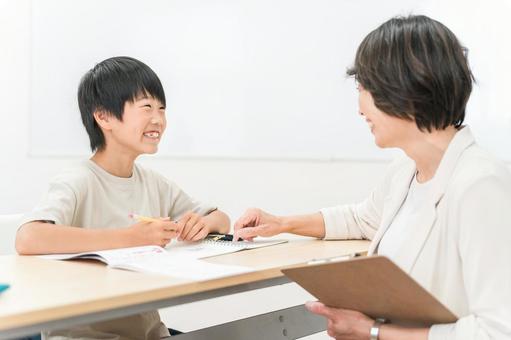 塾・学童で勉強する小学生と女性講師・先生 塾・学童で勉強する小学生と女性講師・先生 塾,小学生,男の子の写真素材