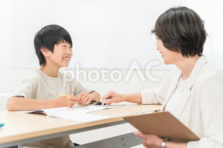 塾・学童で勉強する小学生と女性講師・先生 塾,小学生,男の子の写真素材