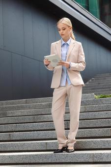 オフィスビルの外の階段でブレットを見ている女性 ビジネスウーマン,ビジネス,女性の写真素材