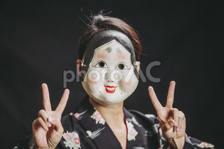 ピースサインをするおかめの女性 おかめ,お面,着物の写真素材