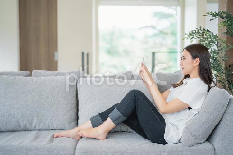 ソファでスマホを使う女性 スマホ,スマートフォン,女性の写真素材