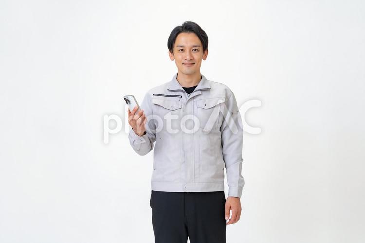 携帯を見る作業着を着た男性 日本人,点検,保守点検の写真素材