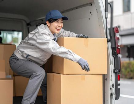 トラックから荷物を出す宅配女性ドライバー トラックから荷物を出す宅配女性ドライバーの写真