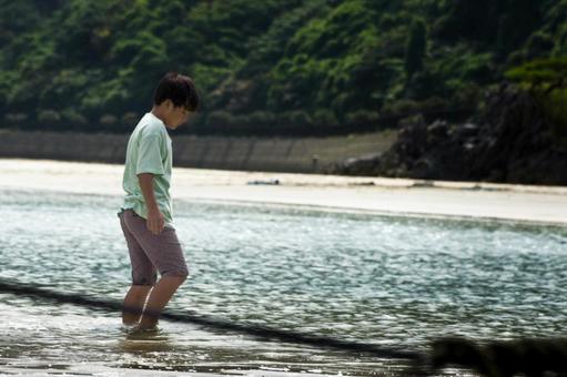 <素材>夕暮れの海で水遊びをする男の子” <素材>夕暮れの海で水遊びをする男の子”の写真