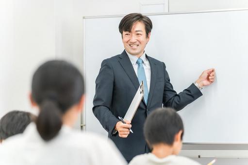 塾・学校で小学生に勉強を教える男性講師 塾・学校で小学生に勉強を教える男性講師 塾,講師,先生の写真素材