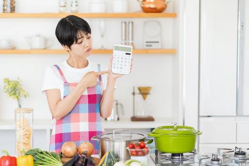 電卓を持って悩む主婦。 電卓を持って悩む主婦。の写真