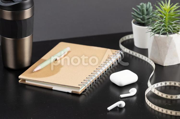 机の上に置かれた白いイヤホンやノート タンブラー,飲み物,コーチングの写真素材