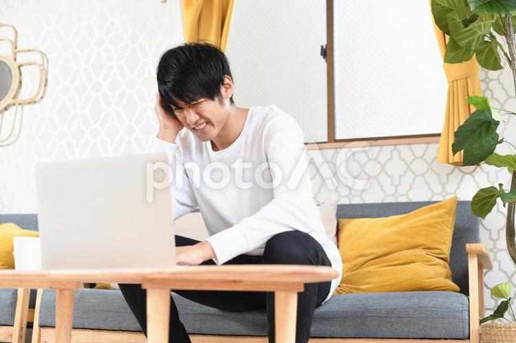 パソコンの前で頭を抱える若い男性 男性,パソコン,トラブルの写真素材