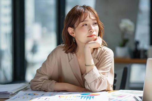 資料を見て悩むビジネス女性 資料を見て悩むビジネス女性の写真