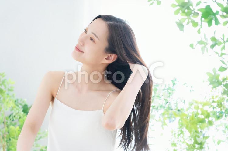 緑の中でヘアケアをする若い女性 ヘアケア,育毛,ビューティーの写真素材