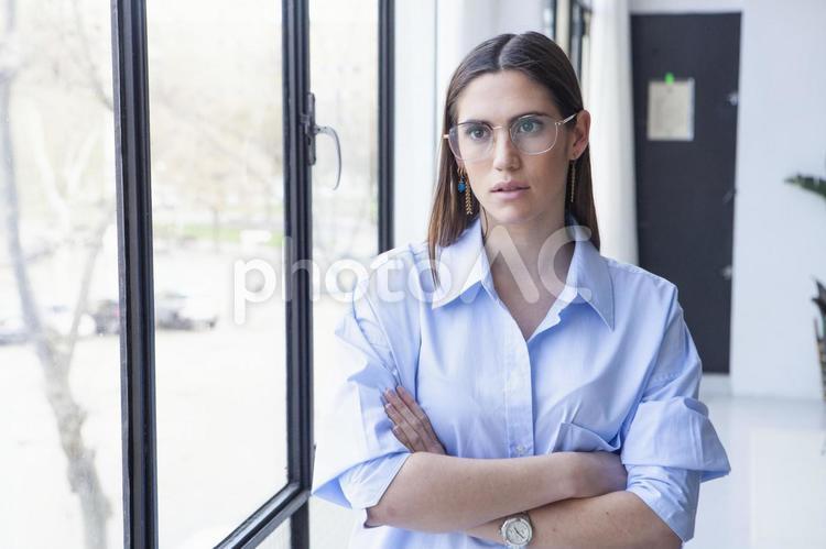 窓際で腕組みをしている眼鏡女性 女性,腕組み,外国人の写真素材