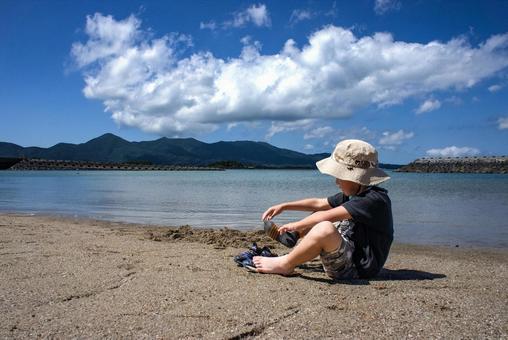 <素材>海に入る前に靴を脱いでいる男の子 <素材>海に入る前に靴を脱いでいる男の子 子供,男性,人物の写真素材