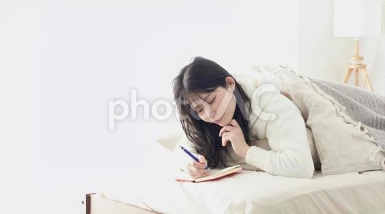 寝ながらメモをとるアジア人女性 女性,書く,メモの写真素材