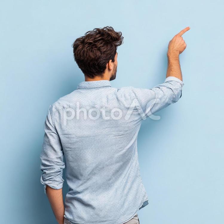 シンプル背景で方向を示す男性の後ろ姿 男性,後ろ姿,指差しの写真素材