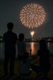 対岸から上る大玉の花火を鑑賞している家族 対岸から上る大玉の花火を鑑賞している家族の写真