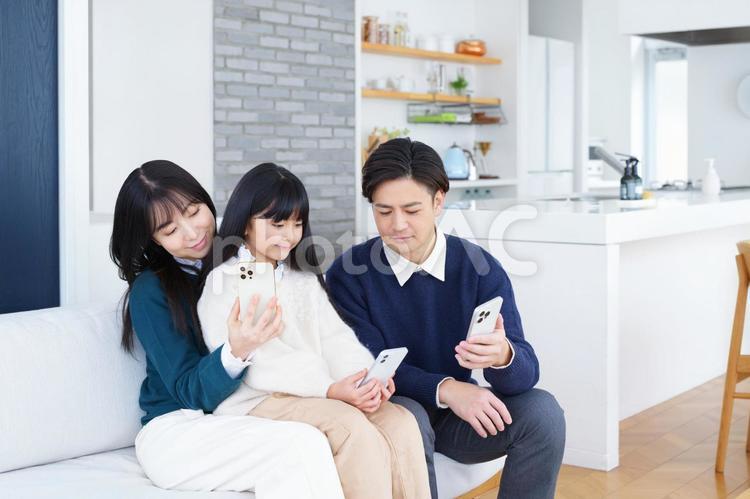 座って携帯を見る家族 家族,男性,女の子の写真素材