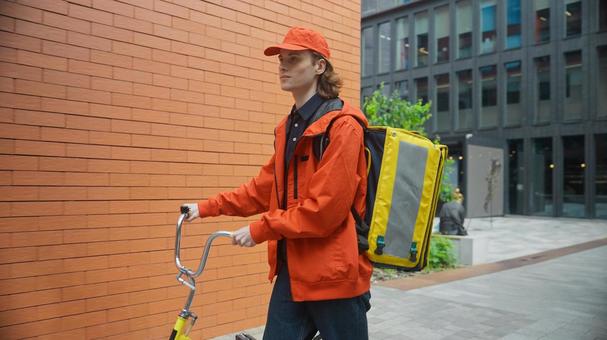 自転車を押して歩くフードデリバリーの男性 配達,フードデリバリー,デリバリーの写真素材