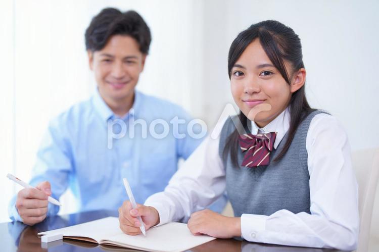 家庭教師と勉強するカメラ目線の女子生徒 人物,男性,家庭教師の写真素材