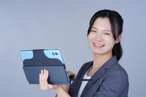 グレーの服の女性が笑顔でタブレットを持つ 女性,タブレット,持つの写真素材